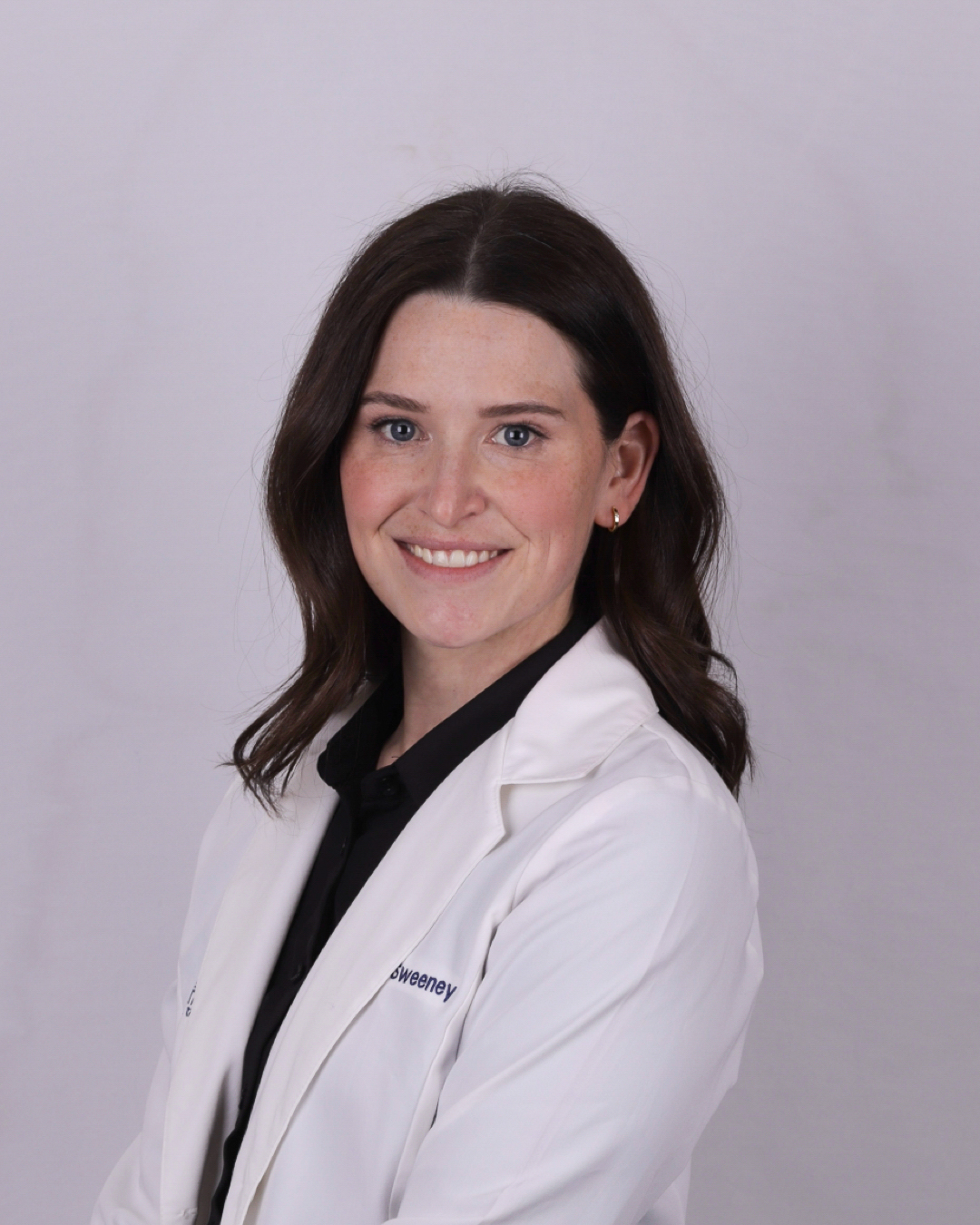 Dr. Erin Sweeney smiling in a white lab coat during a professional headshot for Erin Sweeney DDS PLLC – dentist williamsville ny