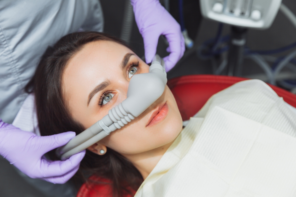 Patient relaxing during sedation dentistry procedure with dental equipment and gloved hands – dentist williamsville ny